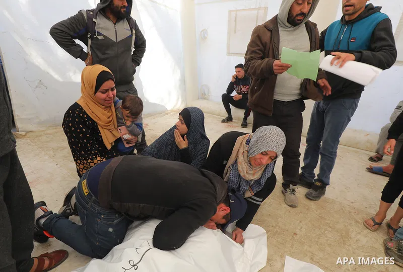 Relatives of the Palestinian Minister of Endowments and former preacher of Al-Aqsa Mosque, Sheikh Youssef Salama, who was killd in Israeli attacks, mourn as they receive his body in the morgue of Al-Aqsa Hospital for bur...