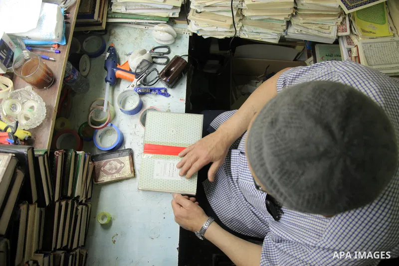 Palestinian man Hisham Barzak, 68, repairs and maintain the Holy Qur'an in a mosque in Gaza City on May 31, 2023. Barzak, repairs and maintain the Holy Qur'an for free in a small room in a mosque, to keep it from damage....