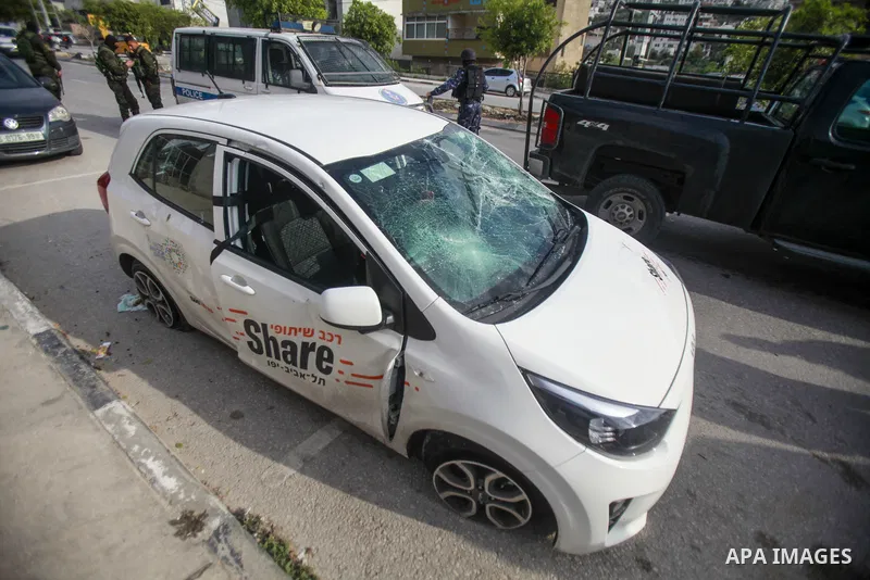 People gather around a car which was destroyed by Palestinian youth in the West Bank city of Nablus on March 18, 2023. According to local source, inside the car were Israeli settlers, while Israeli media said that the ca...