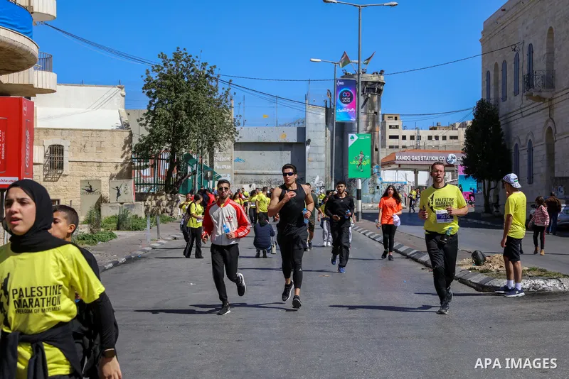 Participants run past a section of Israel's controversial separation barrier during the "Freedom of Movement Palestine Marathon" in Bethlehem in the West Bank on March 10, 2023. Photo by Ahmad Tayem/APAimages