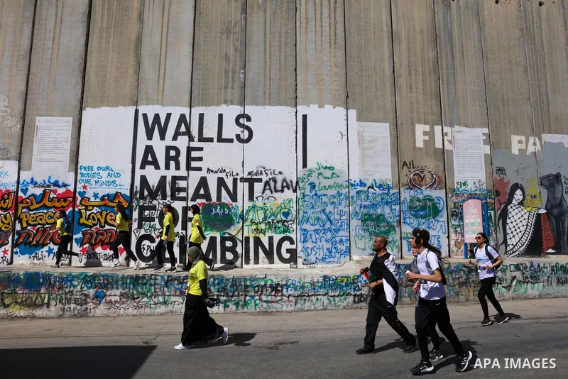 Participants run past a section of Israel's controversial separation barrier during the "Freedom of Movement Palestine Marathon" in Bethlehem in the West Bank on March 10, 2023. Photo by Ahmad Tayem/APAimages
