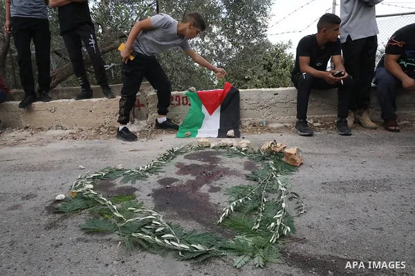 People gather around a blood stain surrounded with leaves near the West Bank city of Tulkarm where two Palestinians were reportedly killed during clashes with Israeli forces on October 5, 2023. Photo by Mohammed Nasser\...