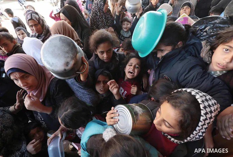 Palestinian people holding empty bowls try to reach out for food distributed by volunteers at donation point as Israeli attacks continue in Dair El-Balah, Gaza on January 26, 2024. The UN Agency for Palestinian Refugees...