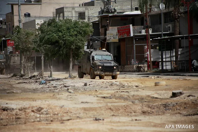 An Israeli armored military vehicle and a heavy machinery move on the road as operations carried out by Israeli forces against Nur Shams Refugee Camp two days ago continue in Tulkarm, West Bank on April 20, 2024. Photo b...