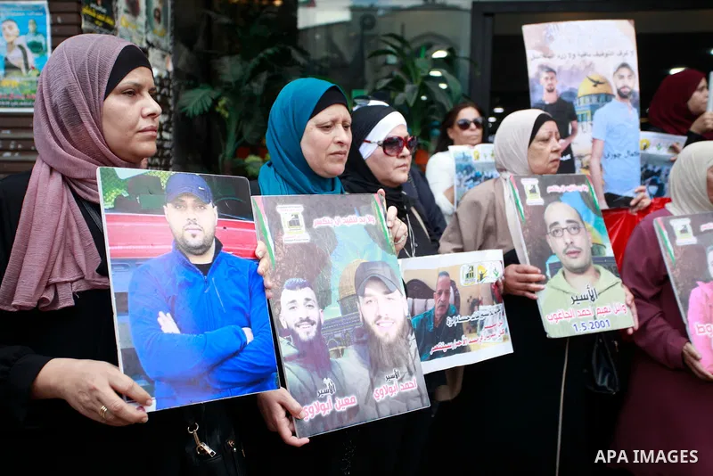 Palestinian women and children hold up framed portraits of relatives jailed in Israel during a sit in to demand their release held in the occupied West Bank city of Nablus on July14, 2024. Photo by Mohammed Nasser\ apaim...