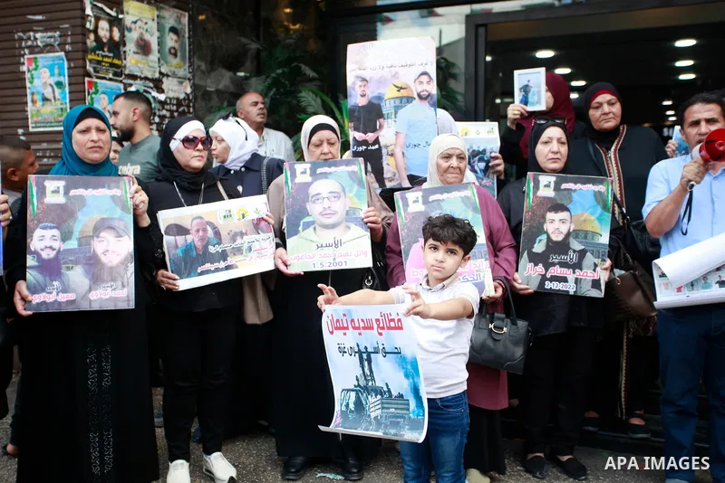 Palestinian women and children hold up framed portraits of relatives jailed in Israel during a sit in to demand their release held in the occupied West Bank city of Nablus on July14, 2024. Photo by Mohammed Nasser\ apaim...