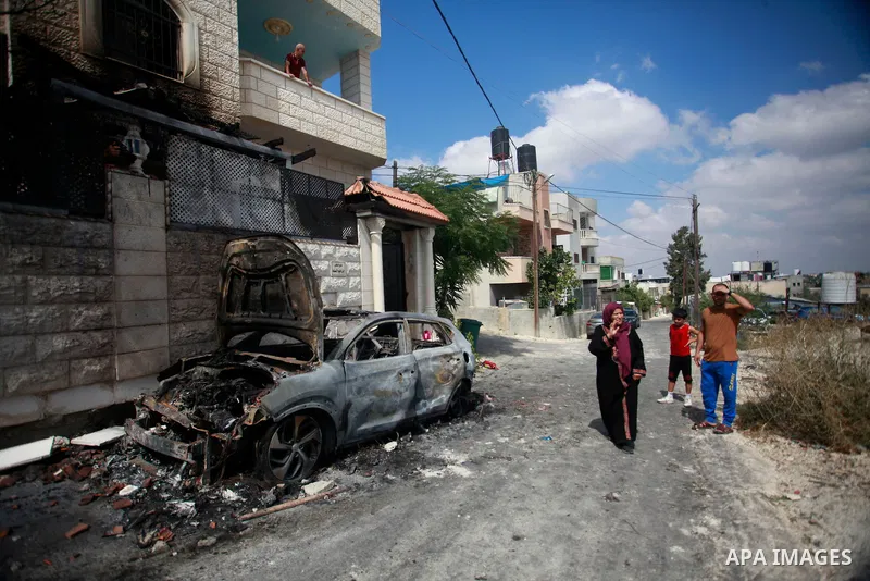 People check a burnt car a day after an attack by Jewish settlers on the village of Jit near Nablus in the occupied West Bank that left a 23-year-old man dead and others with critical gunshot wounds, on August 16, 2024....
