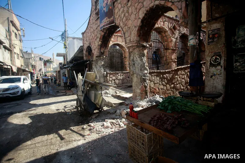 Palestinians walk past damage caused by Israeli army forces during a raid on the Balata refugee camp, near the West Bank city of Nablus, August 18, 2024. Photo by Mohammed Nasser\ apaimages