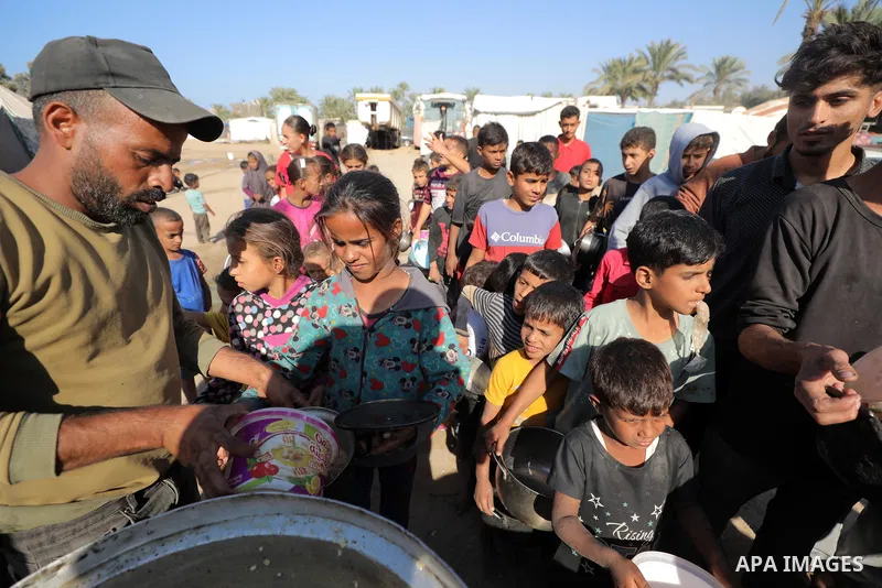 Displaced Palestinians queue to receive food rations, offered by a charity, in Dair El-Balah on October 31, 2024, amid the ongoing war between Israel and the Palestinian militant group Hamas in the besieged Palestinian t...