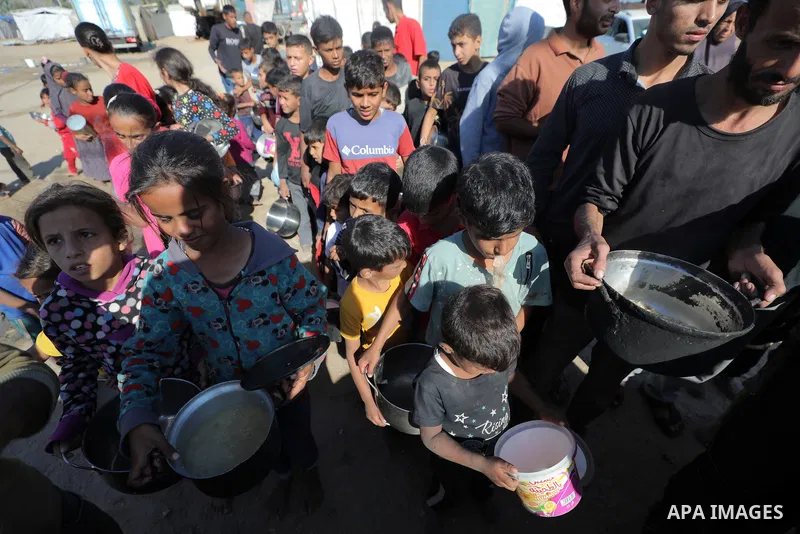 Displaced Palestinians queue to receive food rations, offered by a charity, in Dair El-Balah on October 31, 2024, amid the ongoing war between Israel and the Palestinian militant group Hamas in the besieged Palestinian t...