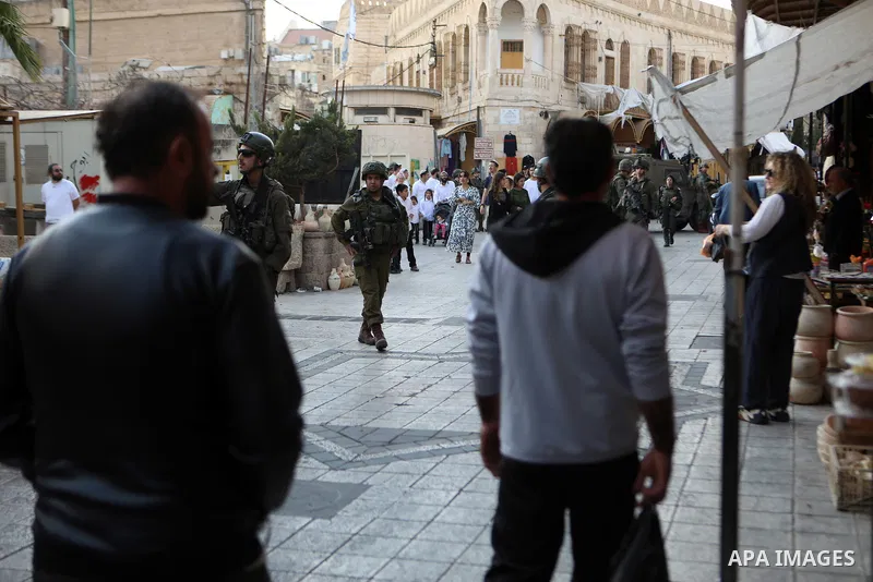 Israeli settlers are escorted by Israeli soldiers during a tour of the market in the Palestinian part of the old city of Hebron in the occupied West Bank on November 02, 2024. Photo by Mamoun Wazwaz\ apaimages