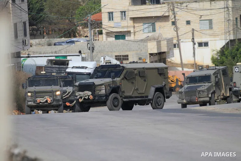 Israeli military vehicles close the street and surround a house where Palestinian gunmen are holed up during a raid to arrest Palestinians in the village of Aqaba near the northern West Bank city of Tubas, where a Palest...