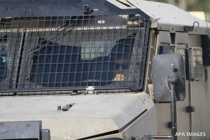 Israeli military vehicles close the street and surround a house where Palestinian gunmen are holed up during a raid to arrest Palestinians in the village of Aqaba near the northern West Bank city of Tubas, where a Palest...