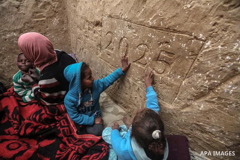 Displaced Palestinian Tayseer Obeid, 41, originally from Gaza City, digs a hole beneath the ground in the Al-Zawaida area of the central Gaza Strip on December 31, 2024. With a shortage of wood and plastic planks to buil...