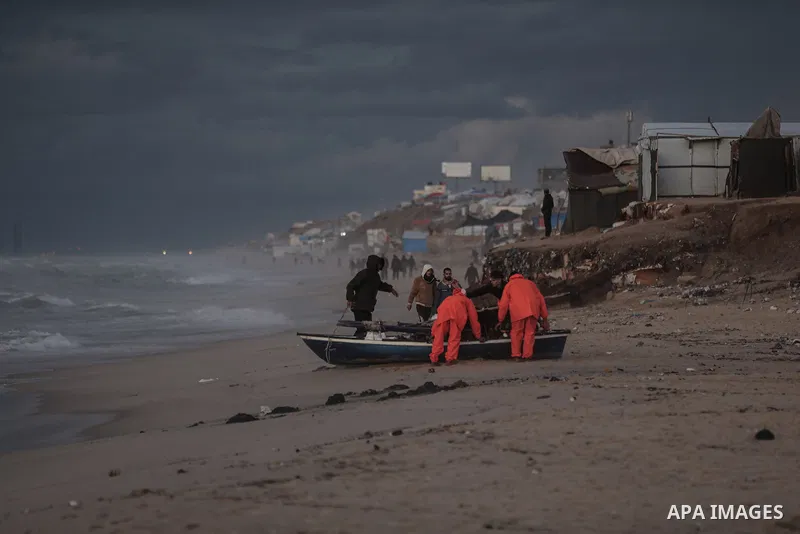 Palestinians walk on the beach during sunset on the last day of 2024 in Deir al-Balah in the central Gaza Strip, on 31 December 2024. Heavy rains in the Gaza Strip, where Israel continues its attacks, caused floods in te...
