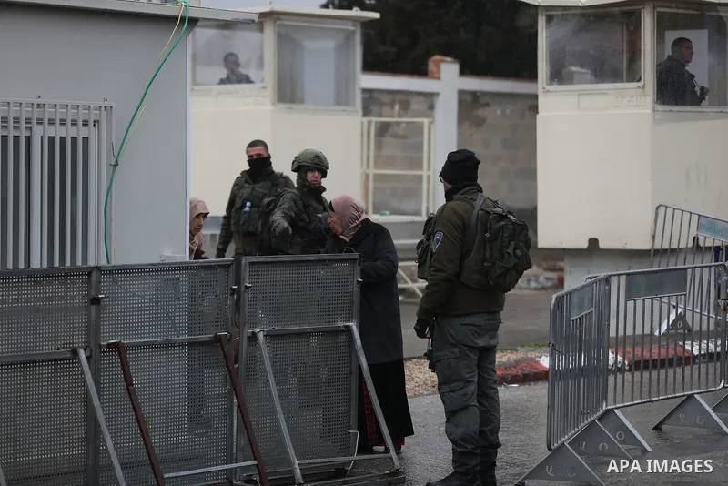 Palestinians walk through an Israeli checkpoint as they make their way to attend the first Friday prayers of the fasting month of Ramadan in Jerusalem's al-Aqsa mosque, in the West Bank city of Bethlehem, March 7, 2025....