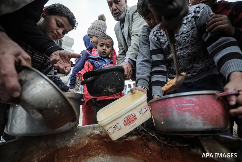 Palestinians wait in long queues to receive pots of food distributed by charitable organizations on the 20th day of Ramadan as they face food crisis, in Deir Al Balah, Gaza on March 20, 2025.Food crisis in the Gaza Strip...