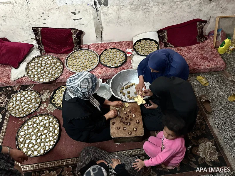 A Palestinian family prepares traditional cookies in preparation for Eid al-Fitr, which marks the end of the holy month of Ramadan, in a shelter for displaced people in a UNRWA school in Khan Yunis, southern Gaza Strip,...