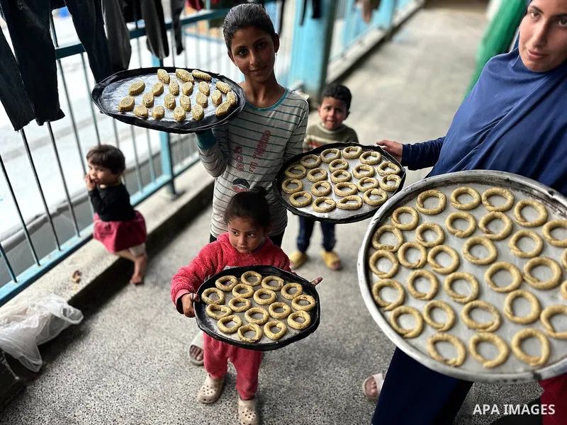 A Palestinian family prepares traditional cookies in preparation for Eid al-Fitr, which marks the end of the holy month of Ramadan, in a shelter for displaced people in a UNRWA school in Khan Yunis, southern Gaza Strip,...