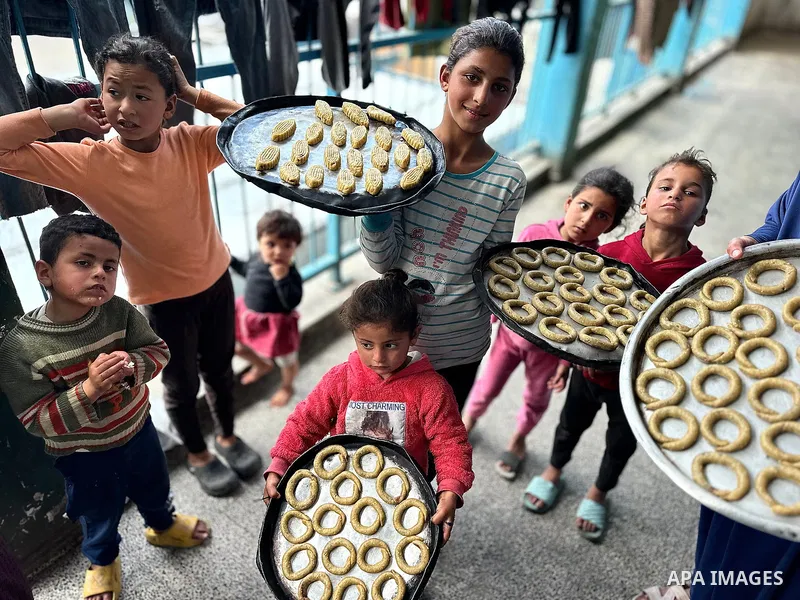 A Palestinian family prepares traditional cookies in preparation for Eid al-Fitr, which marks the end of the holy month of Ramadan, in a shelter for displaced people in a UNRWA school in Khan Yunis, southern Gaza Strip,...