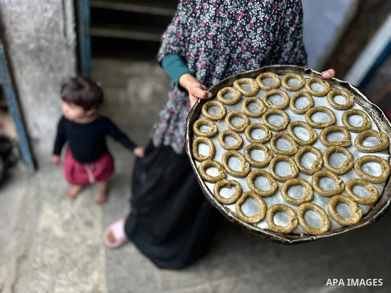 A Palestinian family prepares traditional cookies in preparation for Eid al-Fitr, which marks the end of the holy month of Ramadan, in a shelter for displaced people in a UNRWA school in Khan Yunis, southern Gaza Strip,...