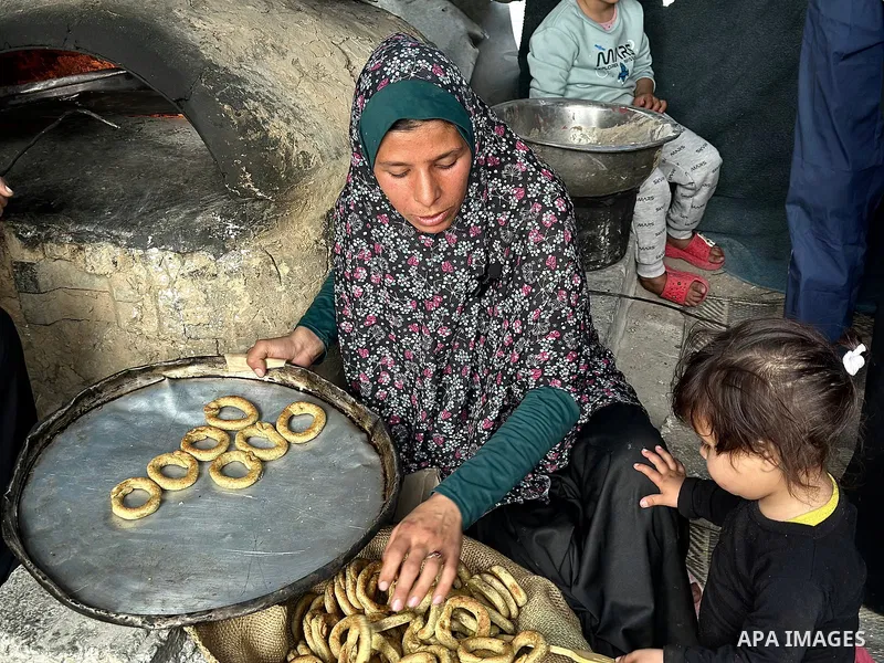 A Palestinian family prepares traditional cookies in preparation for Eid al-Fitr, which marks the end of the holy month of Ramadan, in a shelter for displaced people in a UNRWA school in Khan Yunis, southern Gaza Strip,...