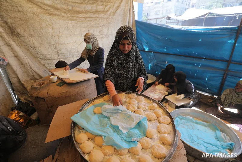 Palestinian women in the Gaza Strip are kneading and baking bread on a saj (traditional griddle) after two months of border crossings being closed by Israeli occupation forces, which has prevented the entry of aid—partic...