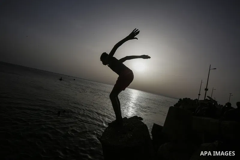 Palestinians, struggling with harsh living conditions due to ongoing Israeli attacks on the Gaza Strip and an intensifying heatwave, gather on the coast to cool off, spending the evening hours by the seaside to escape th...
