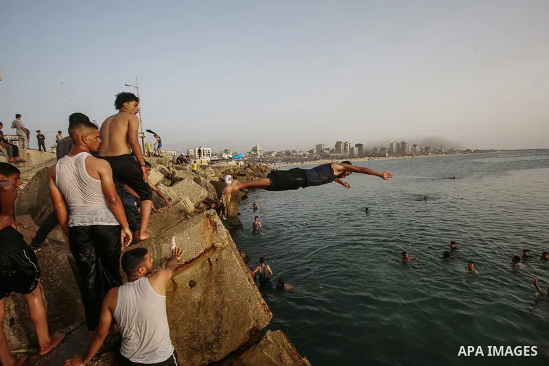 Palestinians, struggling with harsh living conditions due to ongoing Israeli attacks on the Gaza Strip and an intensifying heatwave, gather on the coast to cool off, spending the evening hours by the seaside to escape th...