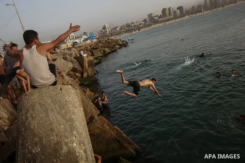 Palestinians, struggling with harsh living conditions due to ongoing Israeli attacks on the Gaza Strip and an intensifying heatwave, gather on the coast to cool off, spending the evening hours by the seaside to escape th...