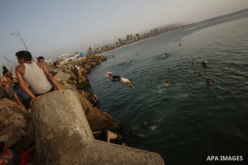 Palestinians, struggling with harsh living conditions due to ongoing Israeli attacks on the Gaza Strip and an intensifying heatwave, gather on the coast to cool off, spending the evening hours by the seaside to escape th...