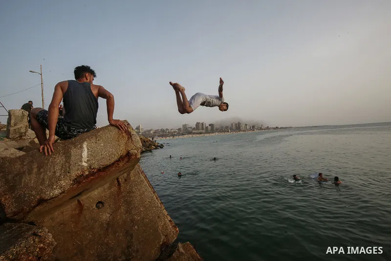 Palestinians, struggling with harsh living conditions due to ongoing Israeli attacks on the Gaza Strip and an intensifying heatwave, gather on the coast to cool off, spending the evening hours by the seaside to escape th...