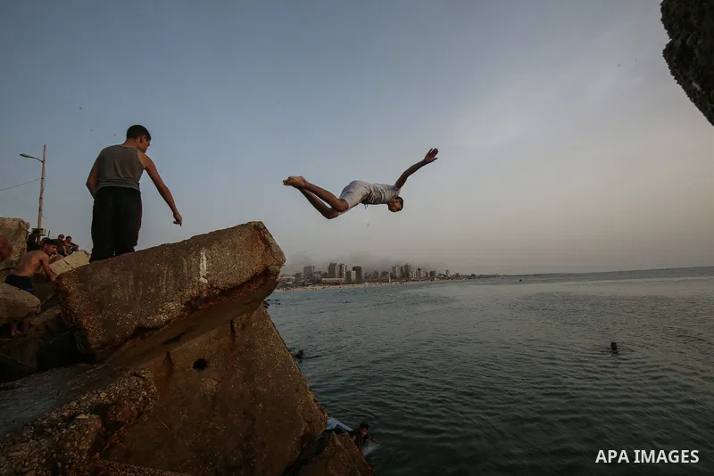 Palestinians, struggling with harsh living conditions due to ongoing Israeli attacks on the Gaza Strip and an intensifying heatwave, gather on the coast to cool off, spending the evening hours by the seaside to escape th...