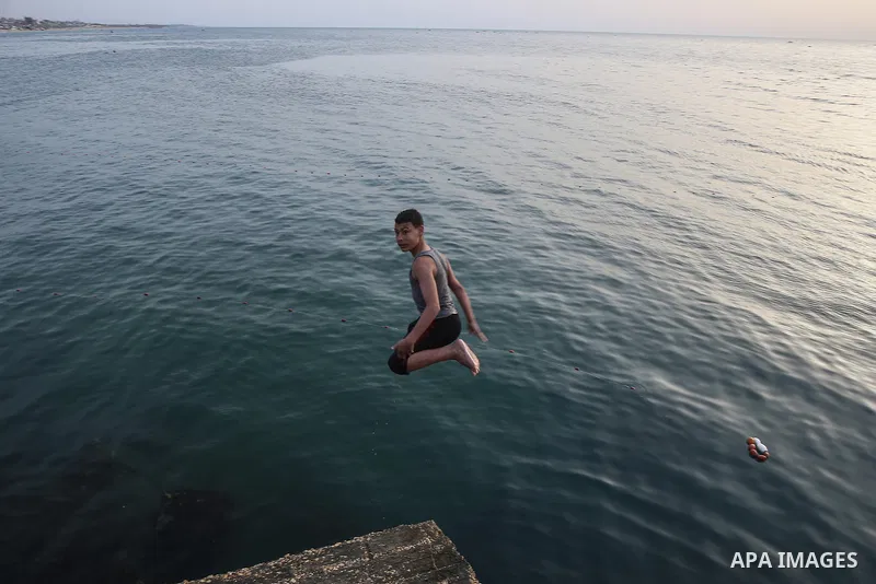 Palestinians, struggling with harsh living conditions due to ongoing Israeli attacks on the Gaza Strip and an intensifying heatwave, gather on the coast to cool off, spending the evening hours by the seaside to escape th...