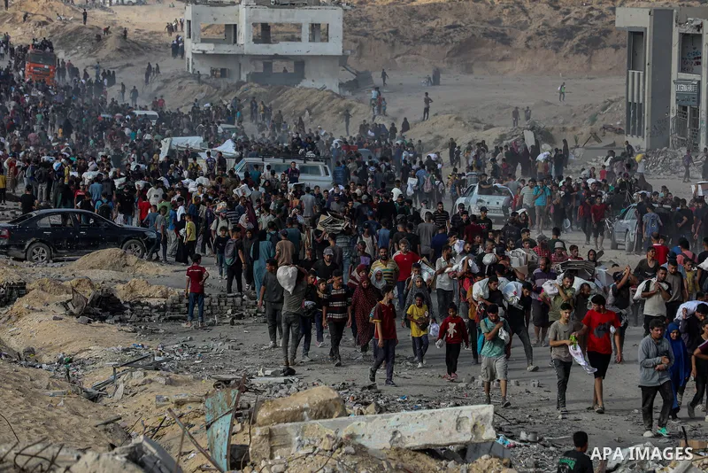 Displaced Palestinians carry relief packages along Rashid Street, west of Jabalia, 22 June 2025, after humanitarian aid trucks entered the northern Gaza Strip through the Israeli-controlled Zikim crossing, northwest of G...