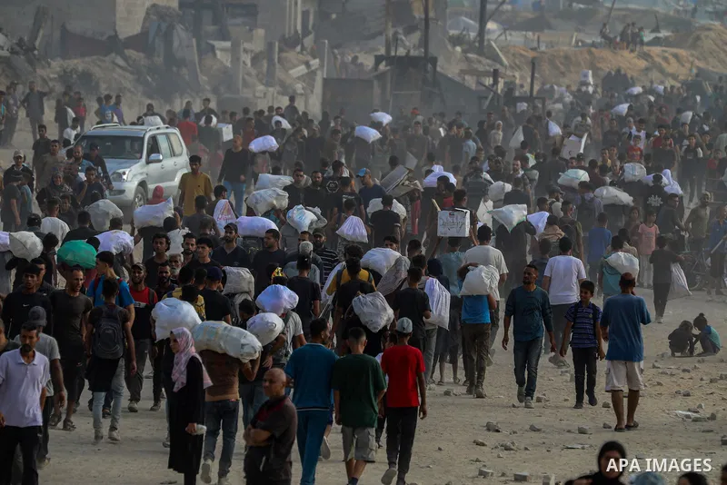 Displaced Palestinians carry relief packages along Rashid Street, west of Jabalia, 22 June 2025, after humanitarian aid trucks entered the northern Gaza Strip through the Israeli-controlled Zikim crossing, northwest of G...