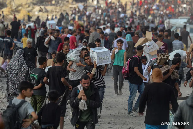 Displaced Palestinians carry relief packages along Rashid Street, west of Jabalia, 22 June 2025, after humanitarian aid trucks entered the northern Gaza Strip through the Israeli-controlled Zikim crossing, northwest of G...