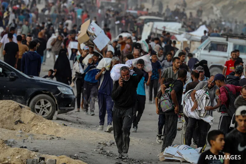 Displaced Palestinians carry relief packages along Rashid Street, west of Jabalia, 22 June 2025, after humanitarian aid trucks entered the northern Gaza Strip through the Israeli-controlled Zikim crossing, northwest of G...