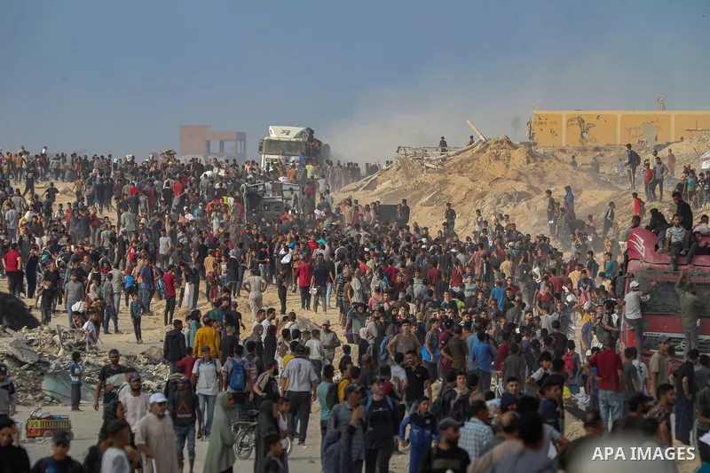 Displaced Palestinians carry relief packages along Rashid Street, west of Jabalia, 22 June 2025, after humanitarian aid trucks entered the northern Gaza Strip through the Israeli-controlled Zikim crossing, northwest of G...