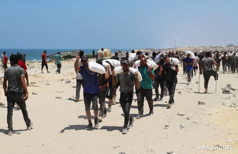 People make their way along al-Rashid street in western Jabalia on July 22, 2025, towards trucks carrying humanitarian aid after they entered the northern Gaza Strip through the Israeli-controlled Zikim border crossing....