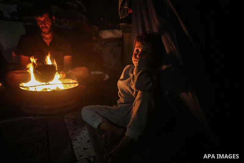 Palestinian families set fire to makeshift tents in Gaza to cope with power shortages, while devastated streets and debris surround their shelters in Gaza City on November 5, 2025. Photo by Omar Ashtawy\ apaimages