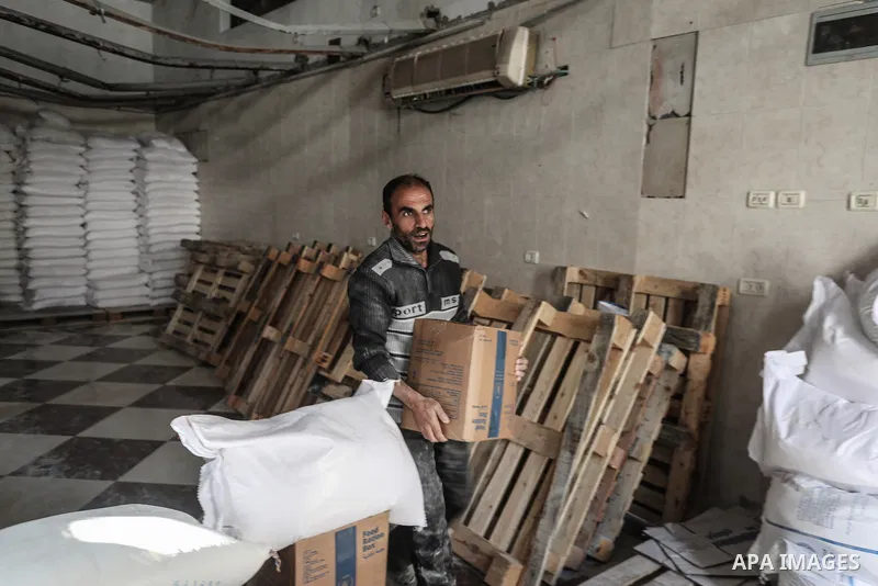 Palestinians collects a flour bags provided by the World Food Programme (WFP), at a distribution centre in Al-Bureij Camp, in the centre of the Gaza Strip on November 18, 2025. Aid agencies complain that humanitarian con...