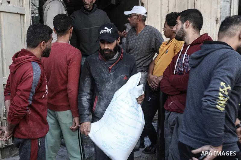 Palestinians collects a flour bags provided by the World Food Programme (WFP), at a distribution centre in Al-Bureij Camp, in the centre of the Gaza Strip on November 18, 2025. Aid agencies complain that humanitarian con...