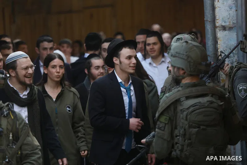 Israeli settlers, under the protection of Israeli forces, raid the Old City of Hebron in the southern West Bank on January 31, 2026. During the raid, Israeli soldiers were seen taking security measures in the area. Photo...