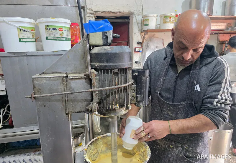 A Palestinian man prepares hummus and falafel, popular Palestinian dishes, during Ramadan in Khan Younis. This particular meal graces tables during Ramadan, despite the shortages of gas and food supplies for the third co...