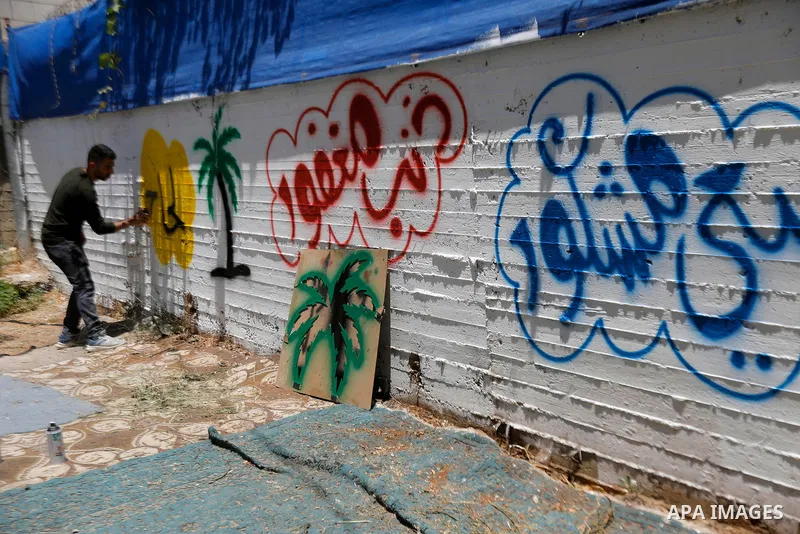 A Palestinian calligrapher paints congratulatory messages along with religious and traditional motifs on the wall of a pilgrim’s home in the West Bank city of Hebron on May 31, 2026, ahead of the pilgrim’s return from pe...