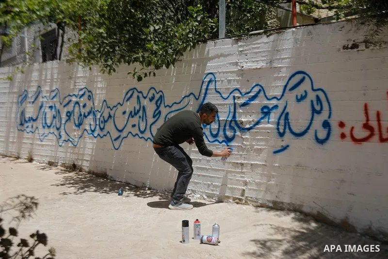 A Palestinian calligrapher paints congratulatory messages along with religious and traditional motifs on the wall of a pilgrim’s home in the West Bank city of Hebron on May 31, 2026, ahead of the pilgrim’s return from pe...