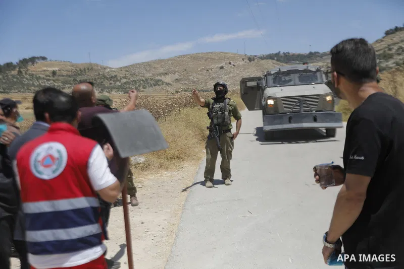 Palestinians and members of the Palestinian Civil Defense gather near the site of a fire on agricultural land around the village of Idhna, west of the West Bank city of Hebron, on June 2, 2026. Palestinian residents said...