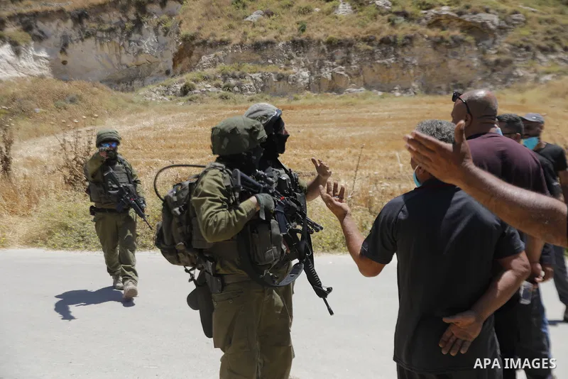 Palestinians and members of the Palestinian Civil Defense gather near the site of a fire on agricultural land around the village of Idhna, west of the West Bank city of Hebron, on June 2, 2026. Palestinian residents said...