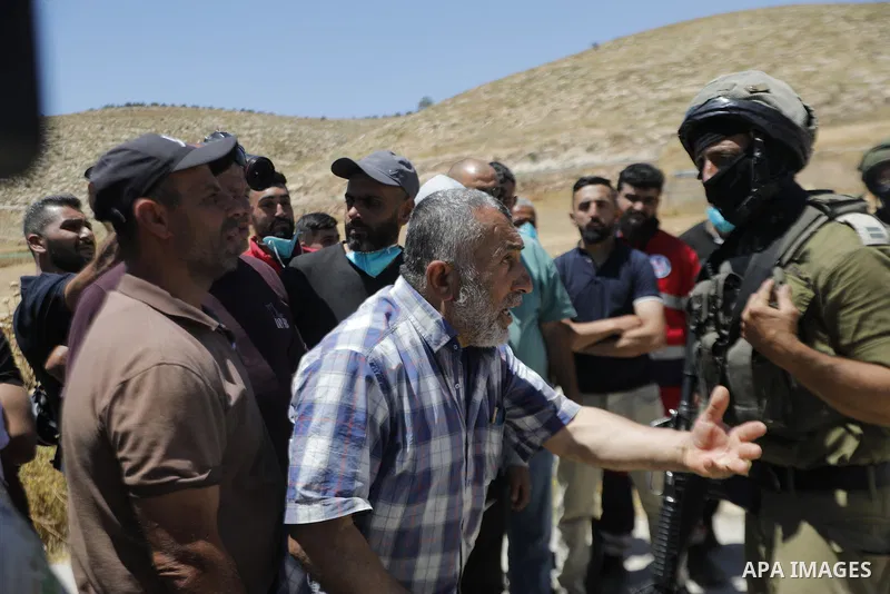 Palestinians and members of the Palestinian Civil Defense gather near the site of a fire on agricultural land around the village of Idhna, west of the West Bank city of Hebron, on June 2, 2026. Palestinian residents said...